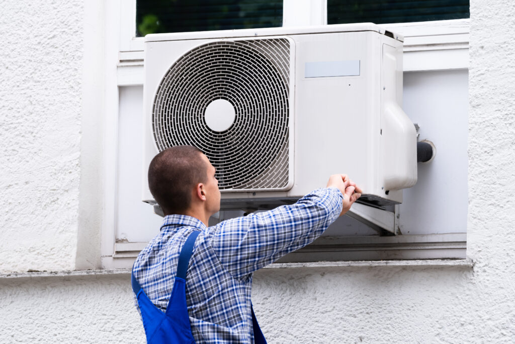 A heating and AC repair technician performing maintenance on an AC unit.