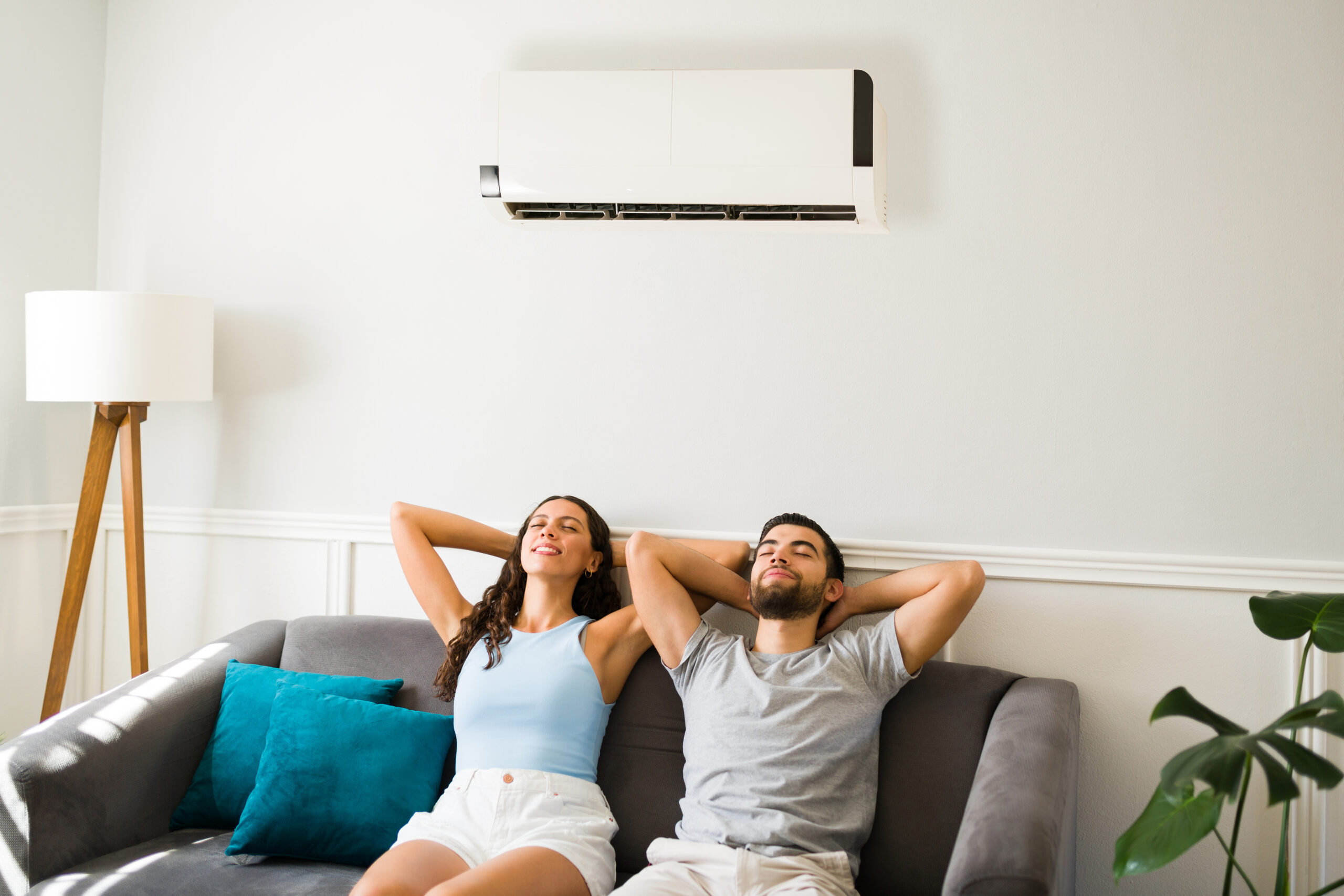 A couple is relaxing and resting on the couch after an air conditioning installation during a hot summer.
