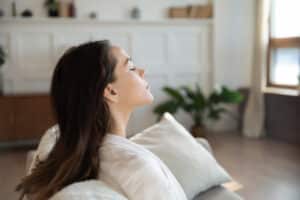 Meditating on sofa with closed eyes breathing cool fresh air satisfied with conditioning humidifying system work, Air Handlers.