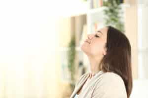 Relaxed woman breathing fresh air at cozy home, HVAC Filtration Techniques.